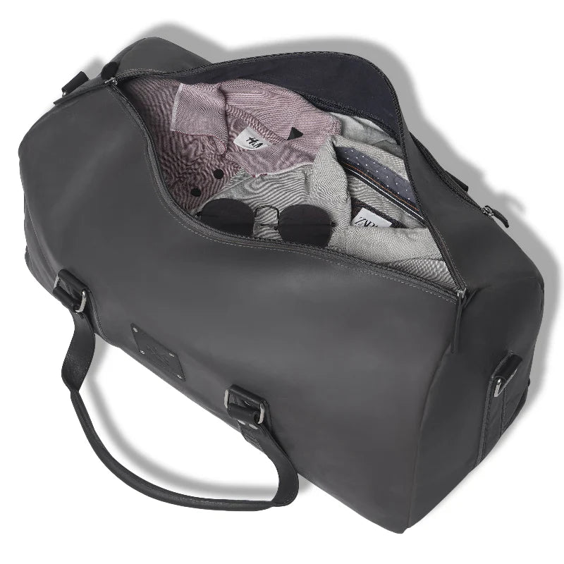 Gray duffel bag with clothes partially inside on a white background