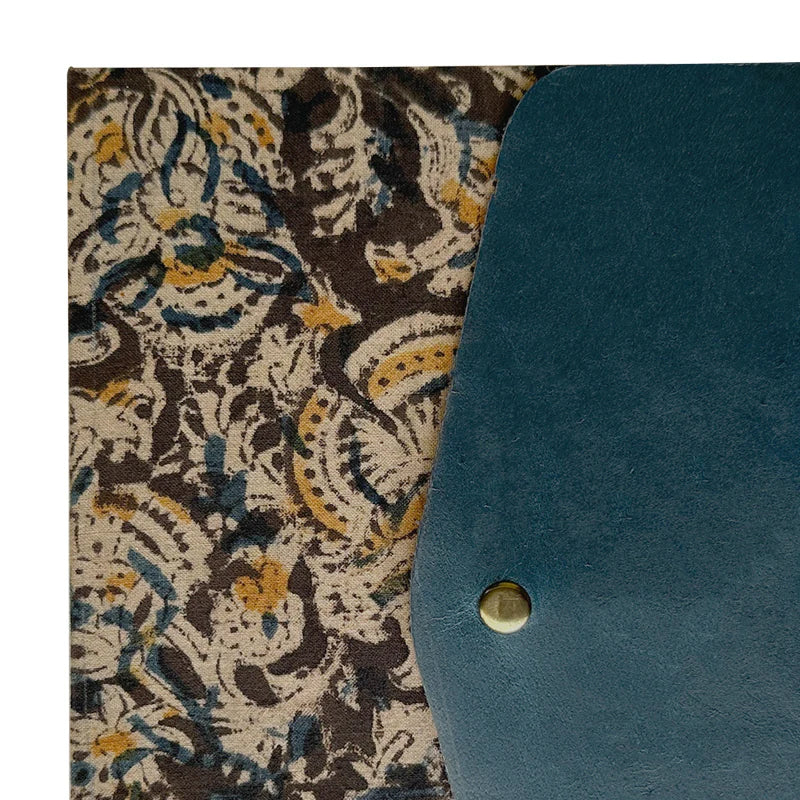 Teal fabric with a gold button on a patterned fabric background