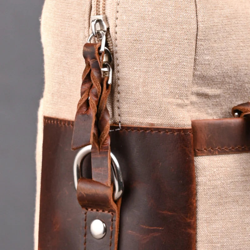 Close-up of a beige and brown leather bag with braided strap and zipper.