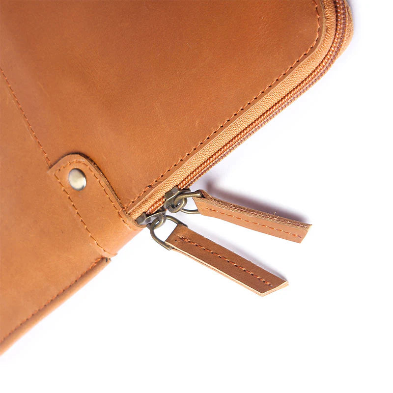 Close-up of a brown leather pouch with a zipper on a white background