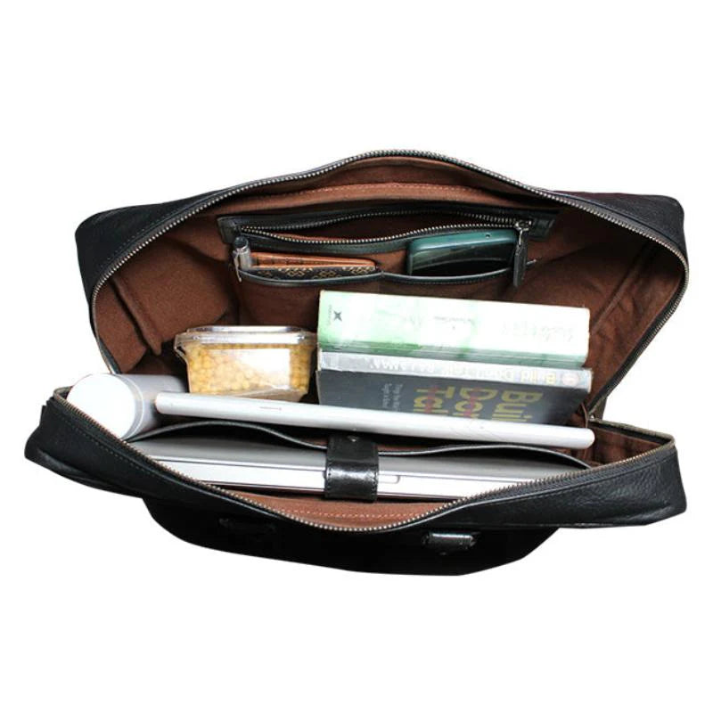 Open black leather briefcase with various items on a white background