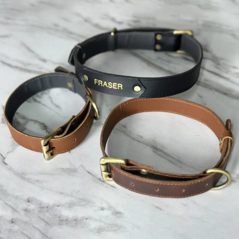 Two leather dog collars, one black and one brown, on a marble surface with &