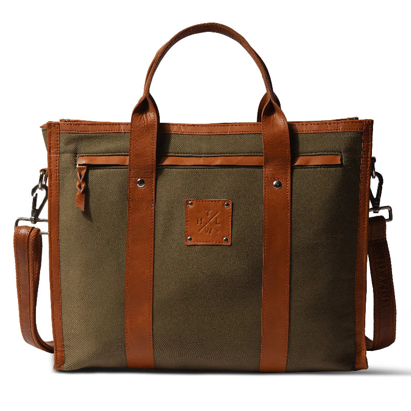 Green canvas bag with brown leather straps and handle on a white background