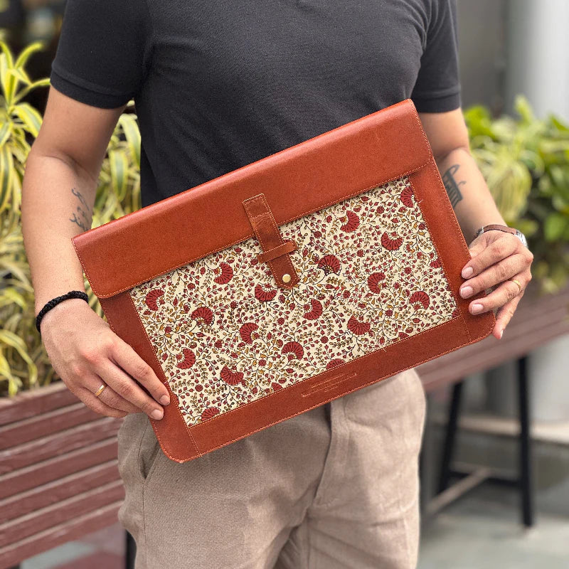 Person holding a brown leather clutch with floral pattern