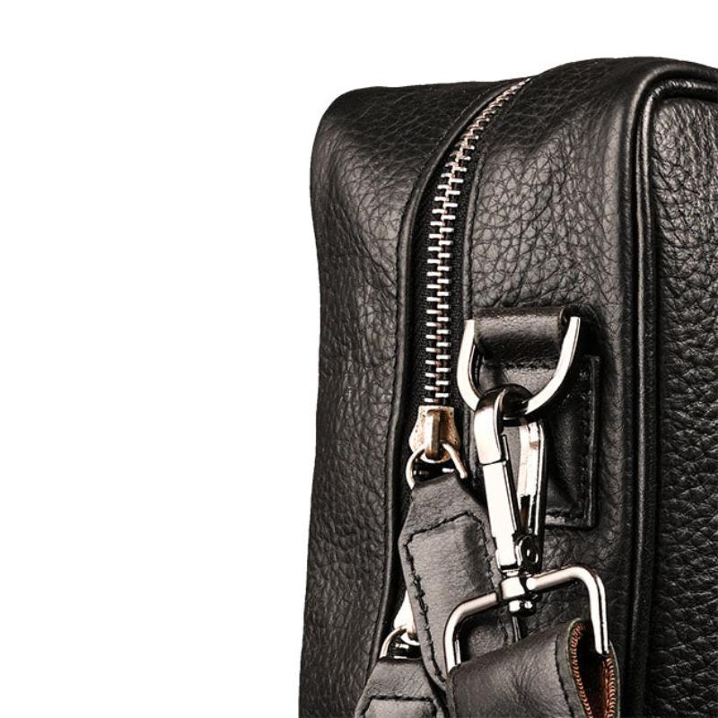 Close-up of a black leather bag with a silver zipper and strap on a white background