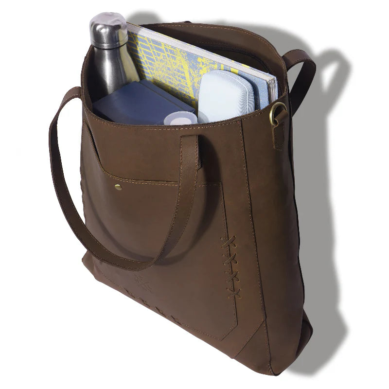 Brown leather bag with items including a water bottle and books on a white background