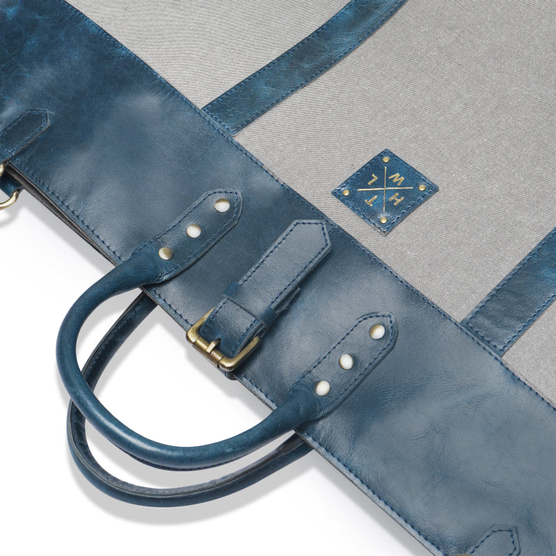 Blue leather bag with a gold buckle on a gray background