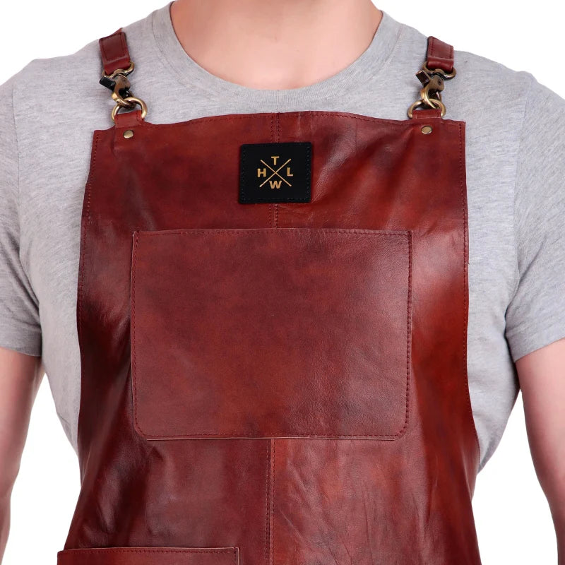 Brown leather apron with a brand logo worn by a person on a white background