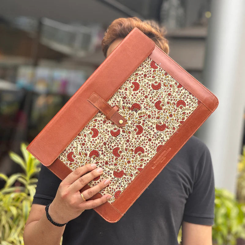 Person holding a floral-patterned folder with a brown leather cover.