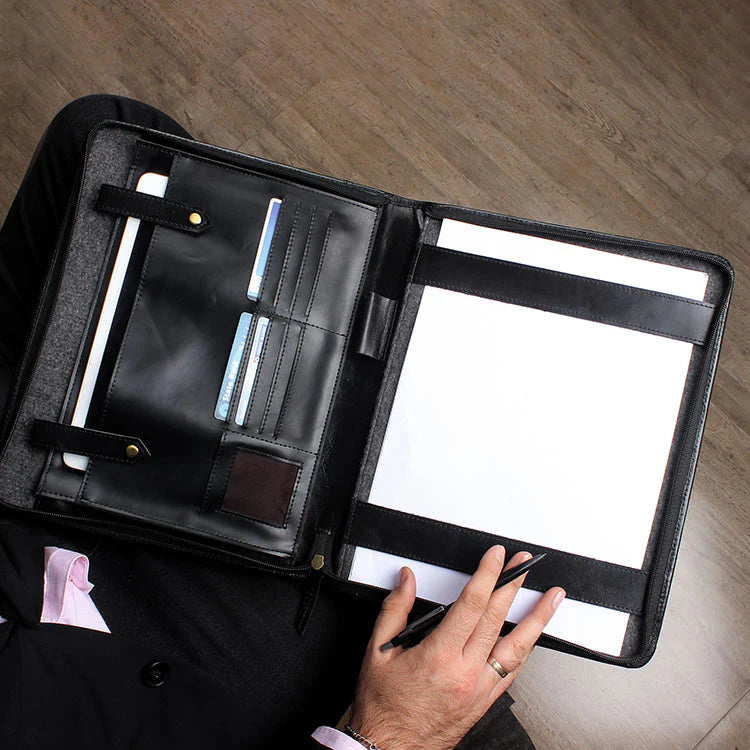 Black leather folder with compartments on a wooden surface