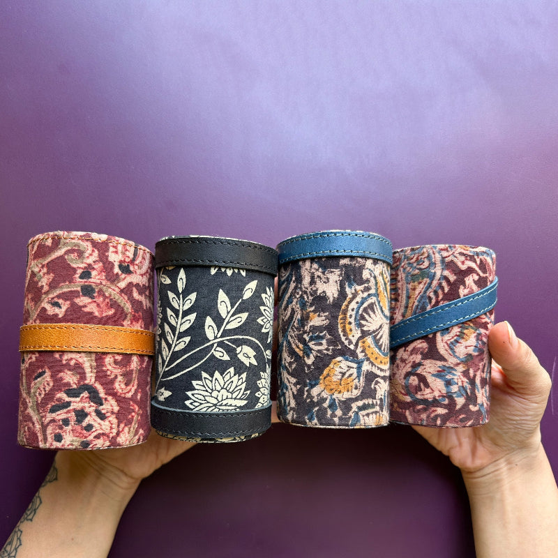 Four fabric-wrapped cylindrical objects held against a purple background