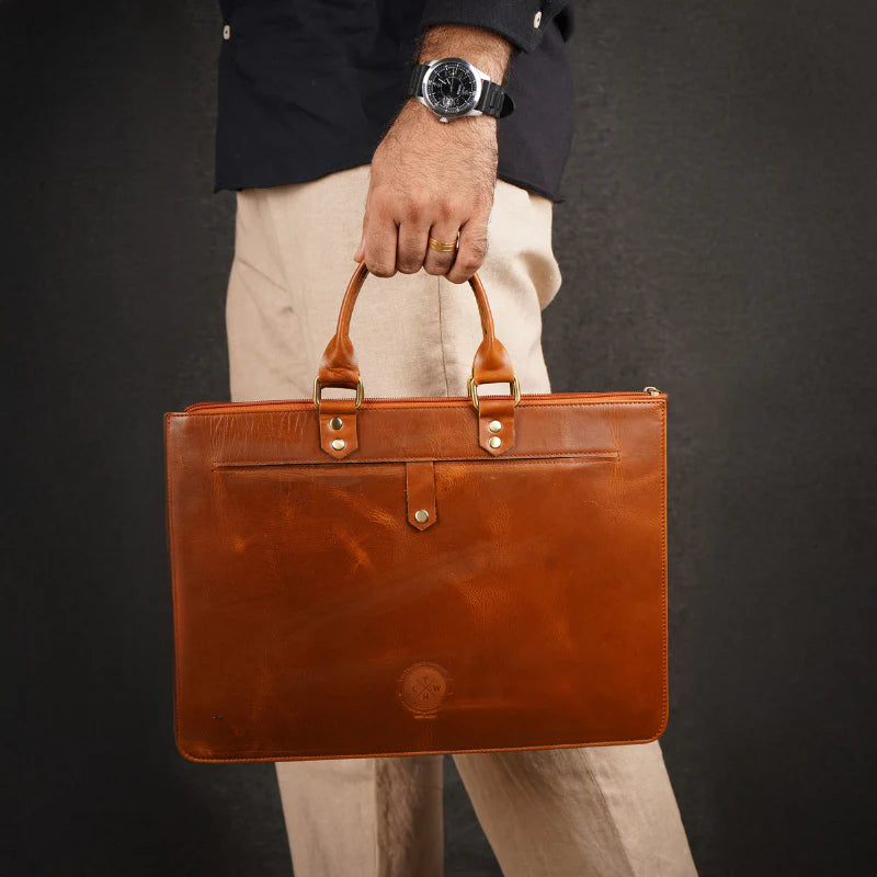 Brown leather briefcase held by a person against a dark background