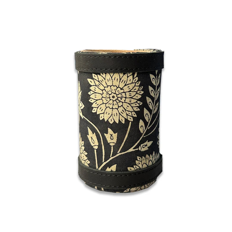 Black cylindrical container with gold floral patterns on a white background