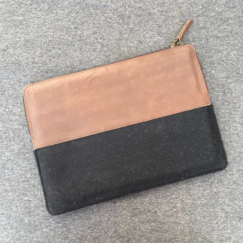 Two-tone clutch bag with rose gold and black sections on a gray surface
