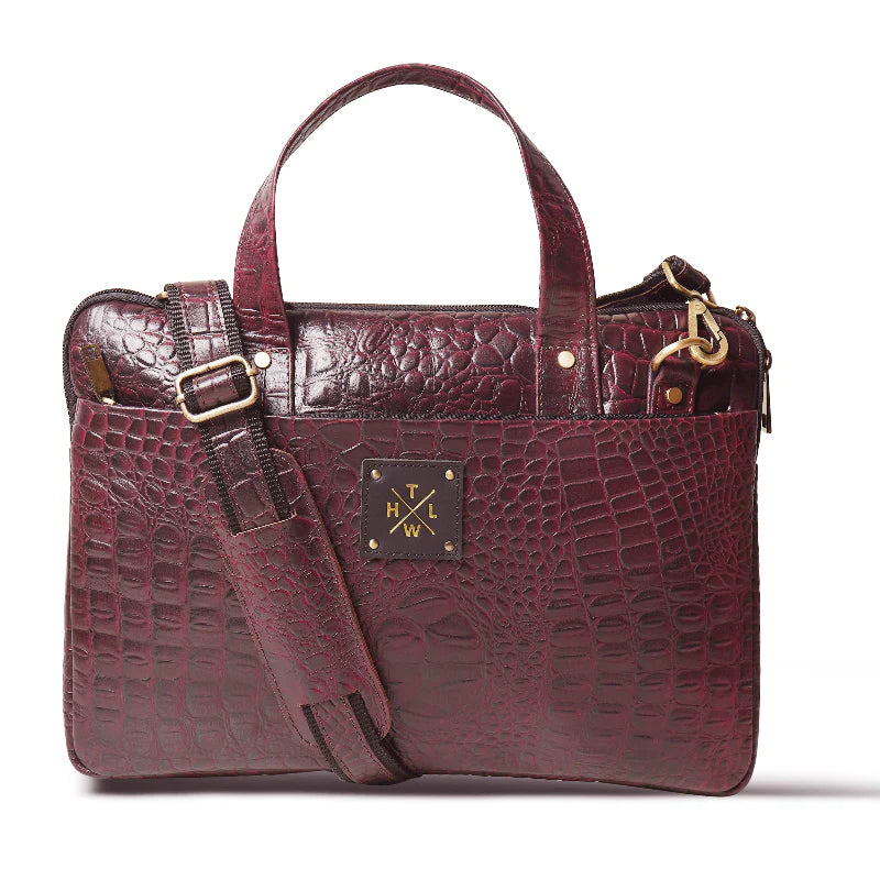 Maroon textured handbag with gold accents on a white background
