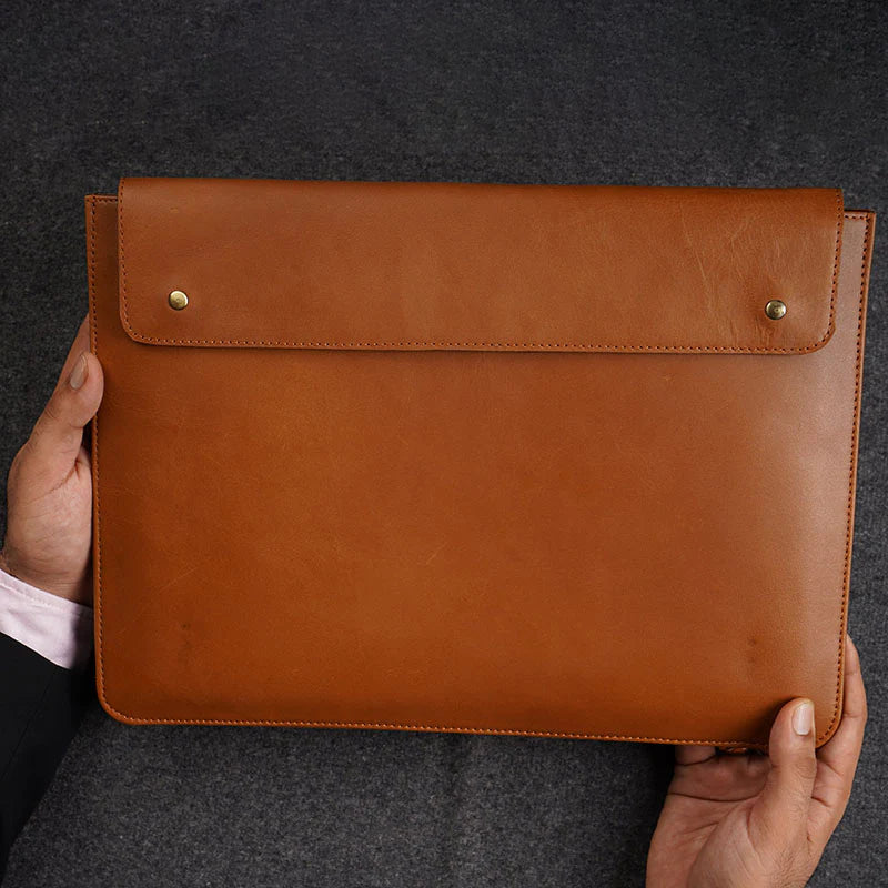 Brown leather envelope held by a person against a dark background