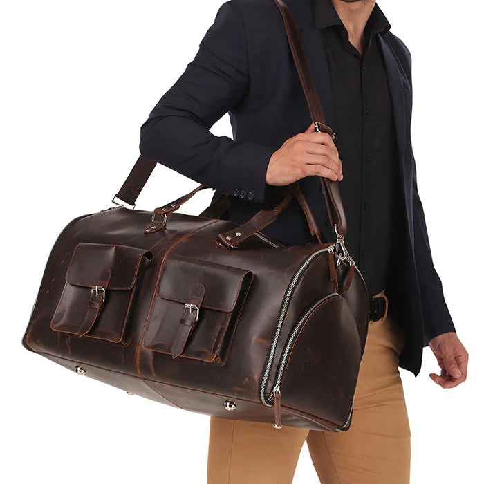 Man holding a brown leather duffel bag against a white background