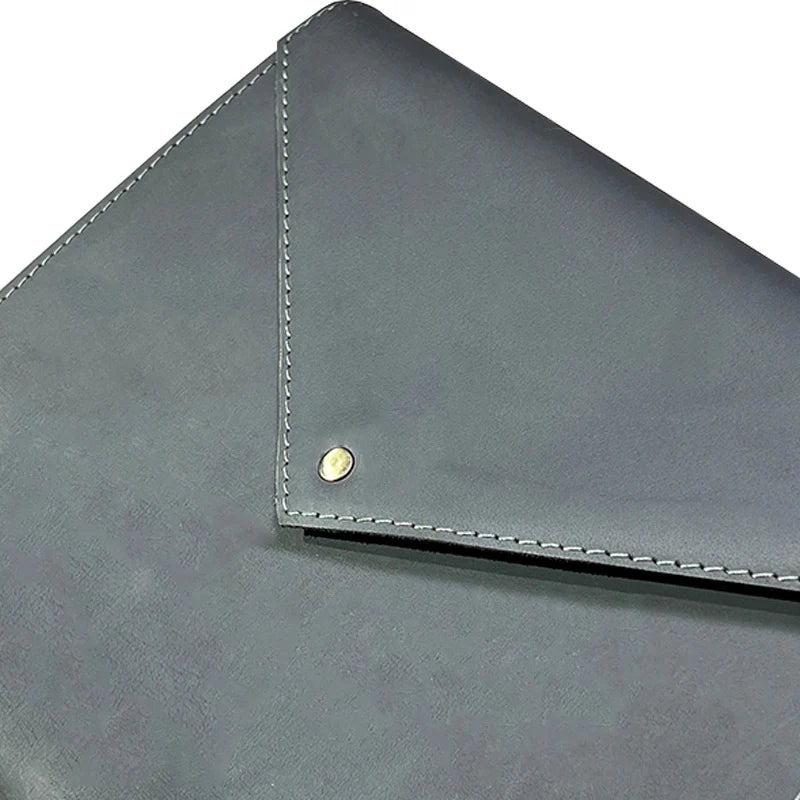 Close-up of a gray leather clutch with gold stud detail on a white background