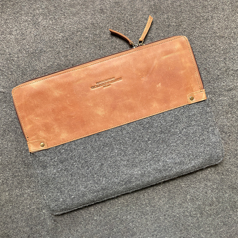 Two-toned pouch with brown leather top section and gray fabric bottom section on a gray surface.