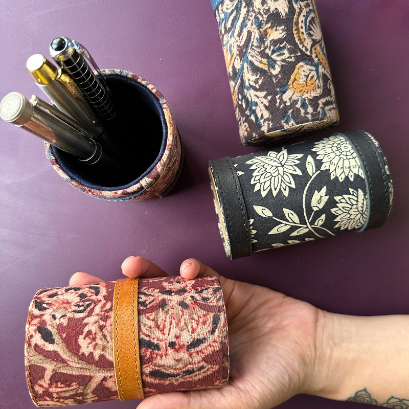 Decorative cylindrical containers with floral patterns on a purple surface.