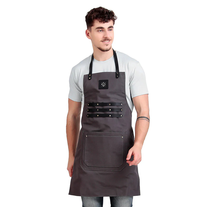 Man wearing a gray apron with black straps on a white background