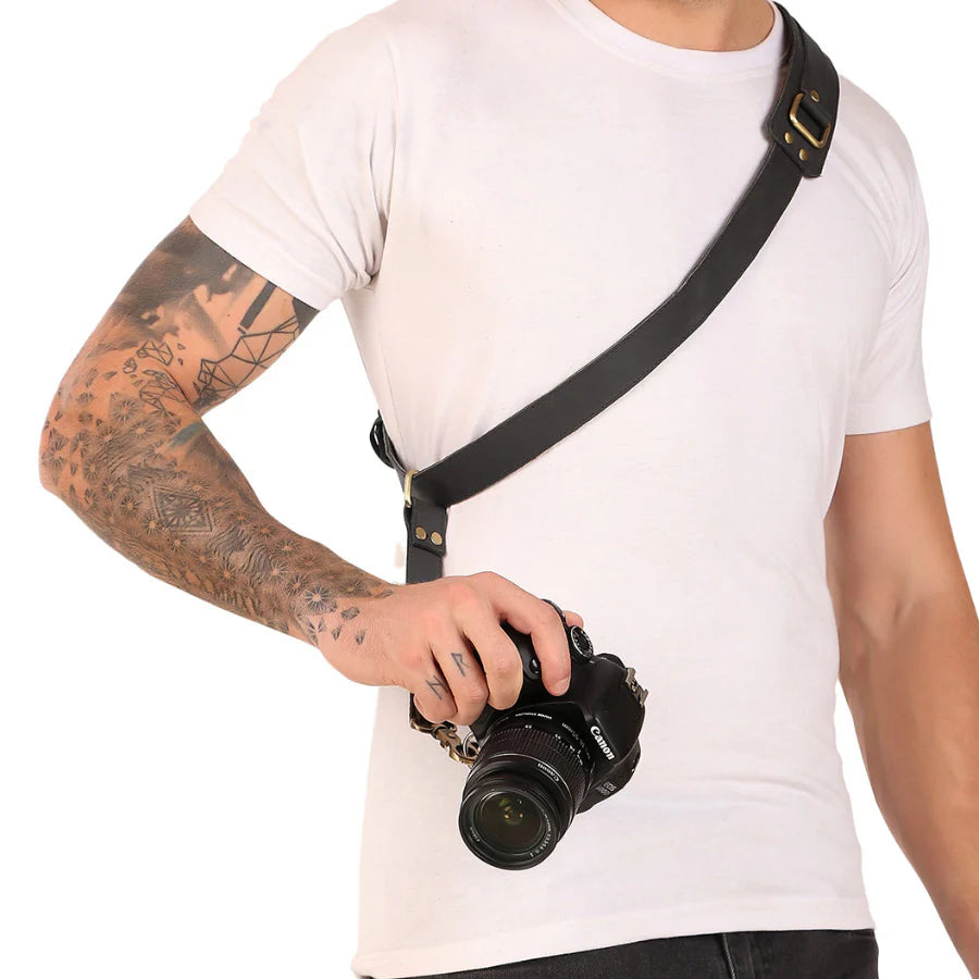 Person holding a camera with a black strap on a white background