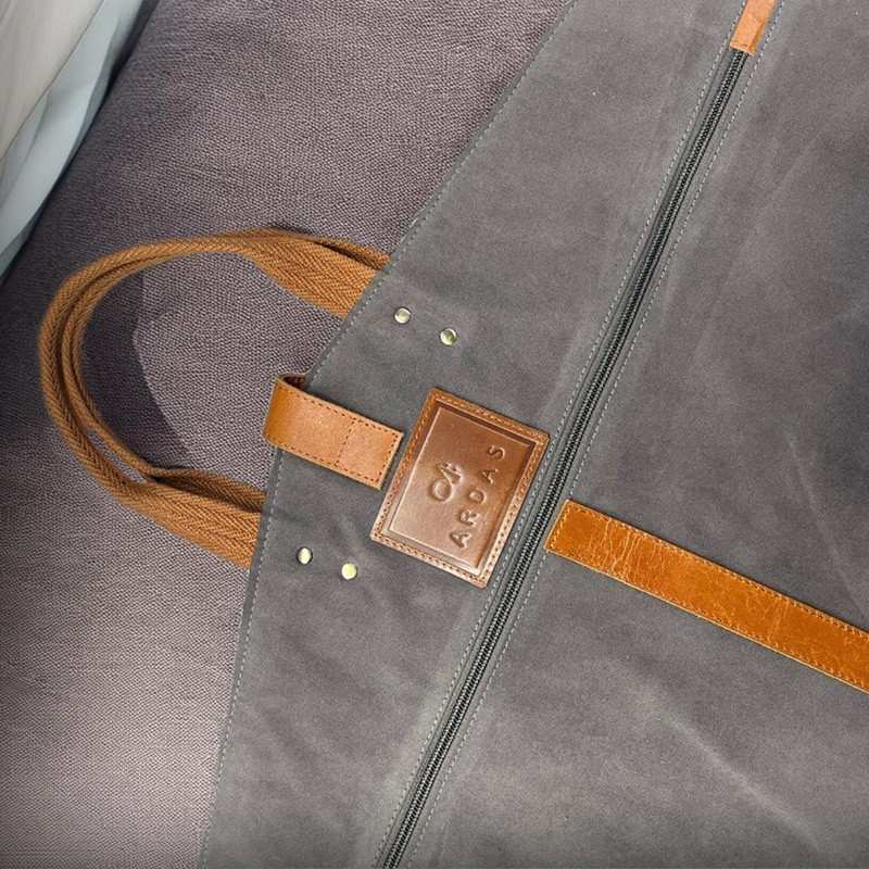 Gray bag with brown leather accents and a brand logo on a gray background