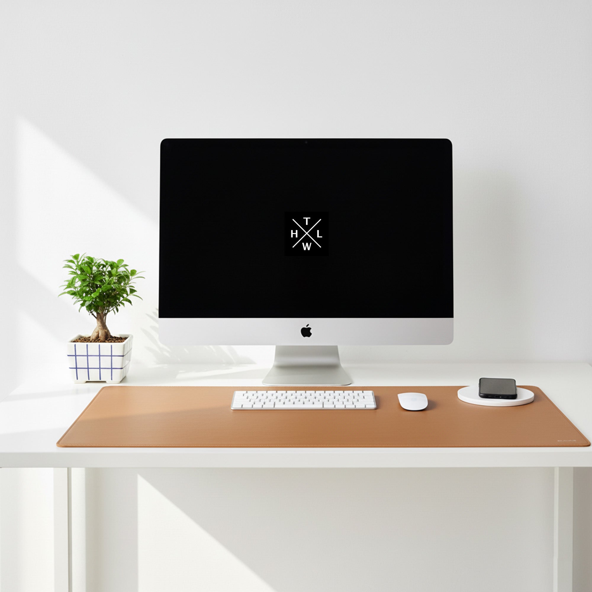 Modern desk setup with a computer monitor, keyboard, mouse, and phone on a wooden desk pad.