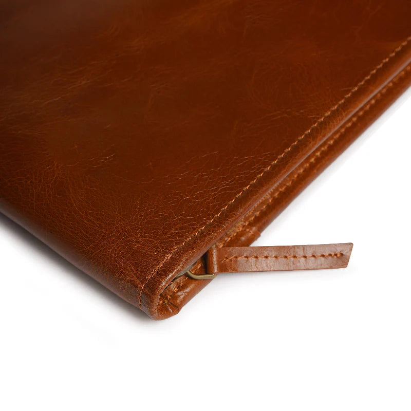 Close-up of a brown leather notebook with a zipper on a white background