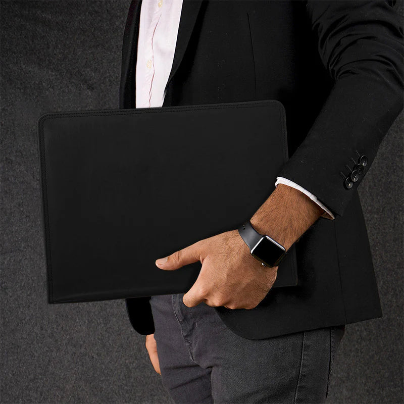 Person holding a black leather briefcase against a dark background