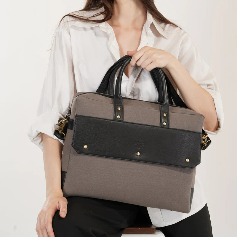 Person holding a gray and black handbag against a white background