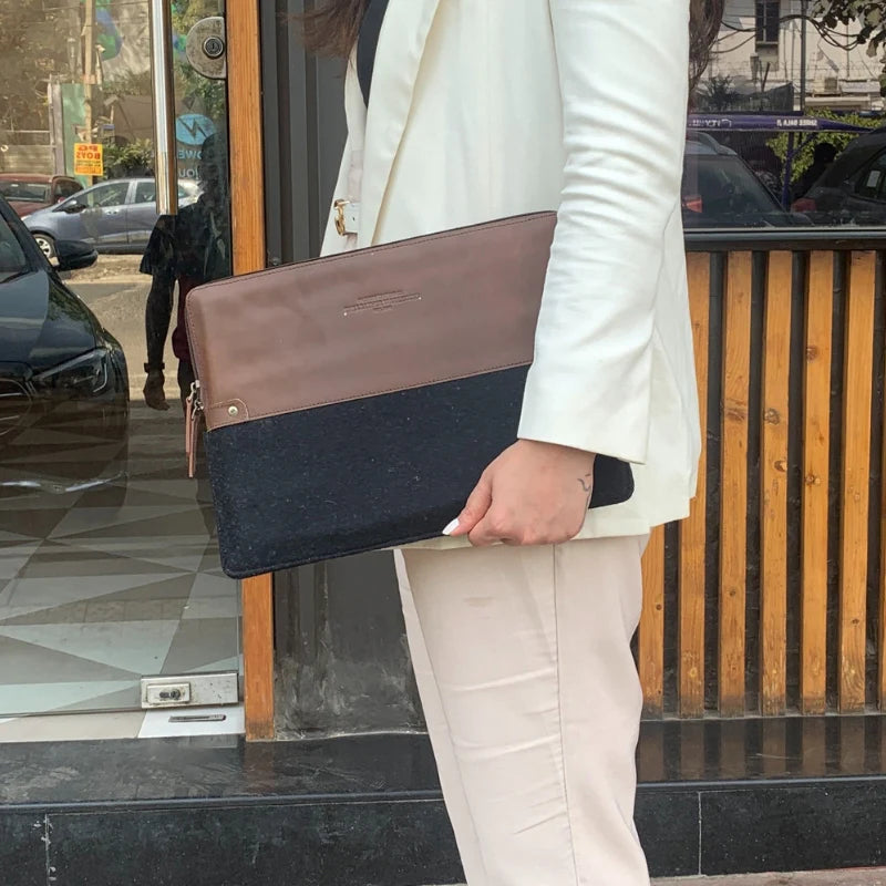 Person holding a two-tone clutch bag in an urban setting