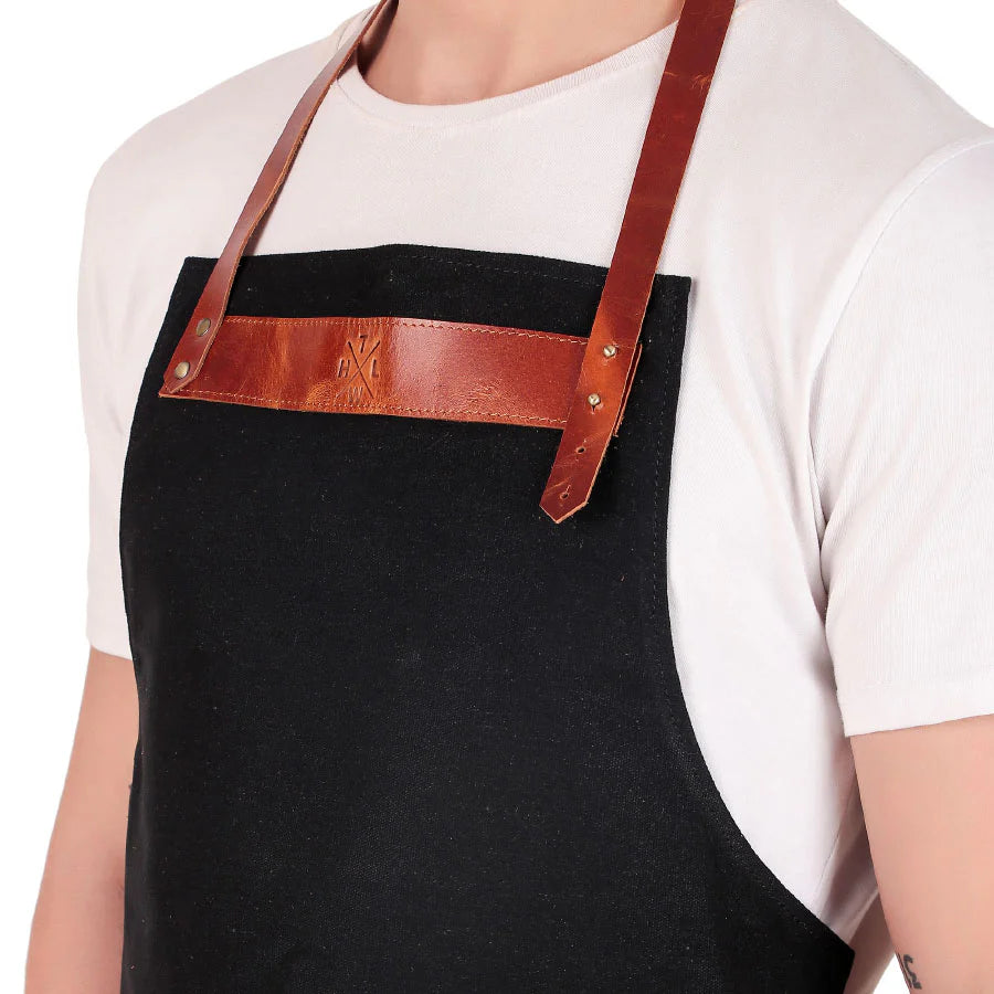 Person wearing a black apron with a brown leather strap on a white background