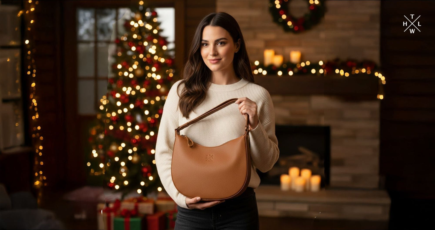 A woman holding a tan leather sling bag in a cozy Christmas setting with lights a tree and festive decor showing warm Christmas gifts for women sling bag.