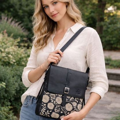Woman holding a black crossbody bag with floral pattern outdoors
