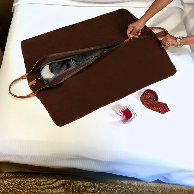 Brown travel bag with a tie and other items on a white surface