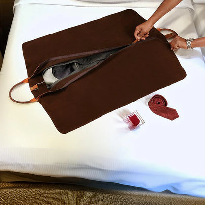 Brown travel bag with a tie and other items on a white surface