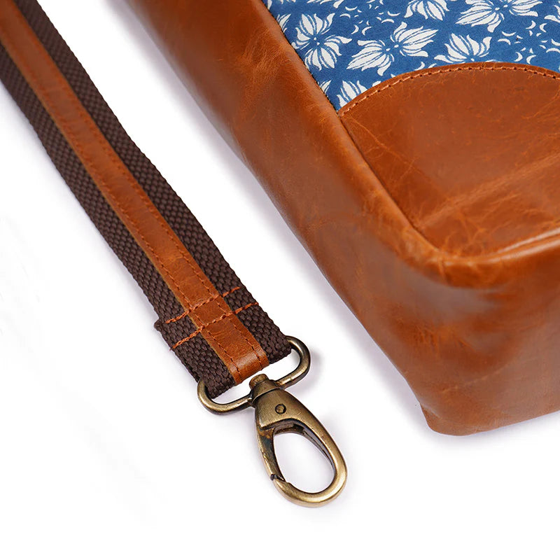 Brown leather bag with a strap and clasp on a white background