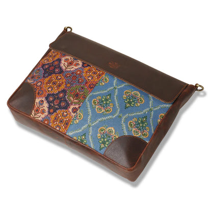Multicolored patterned pouch with brown leather accents on a white background