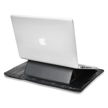 Laptop on a black crocodile-patterned stand sleeve with an Apple logo visible