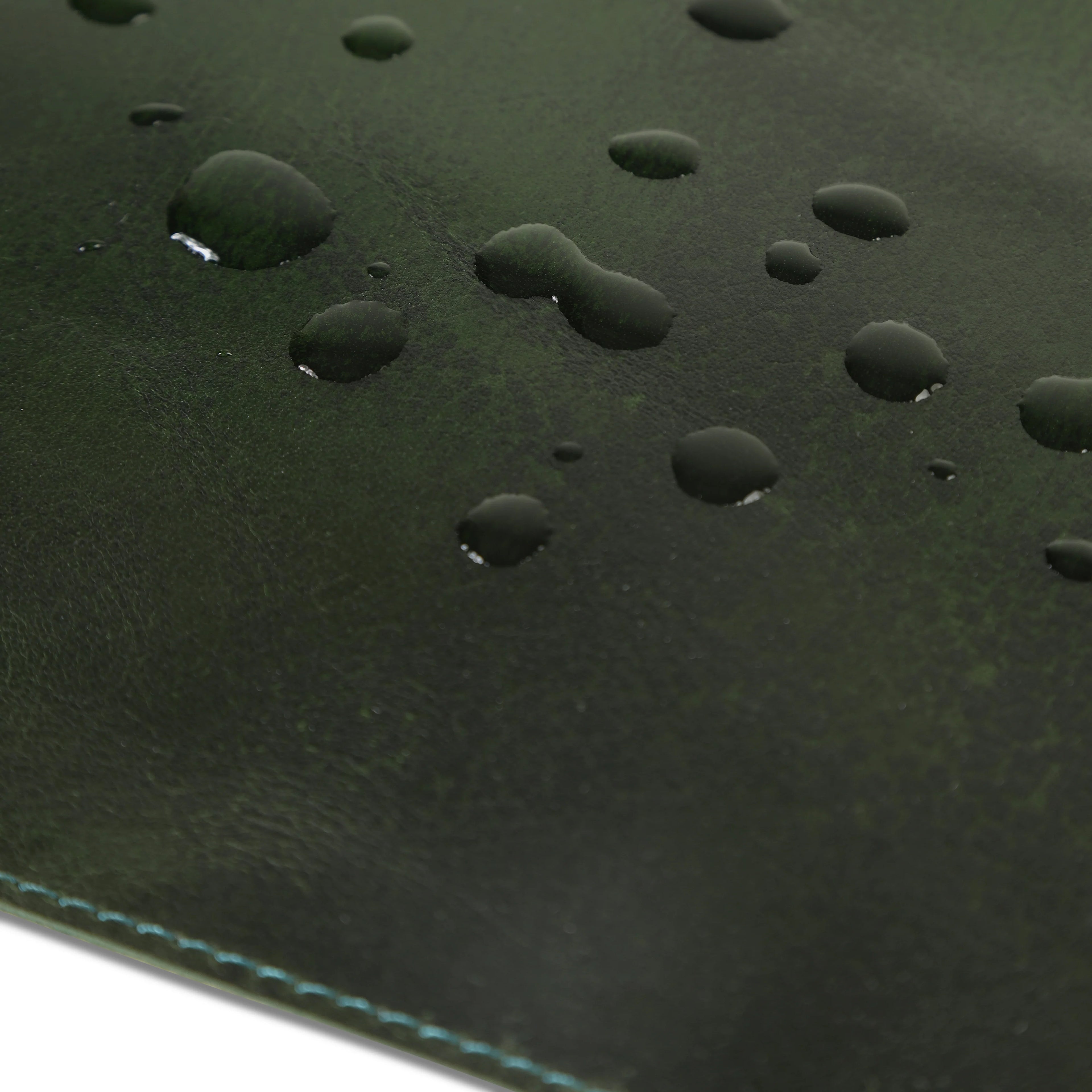 Close-up of a green leather desk mat with water droplets.