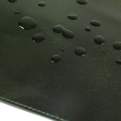 Close-up of a green leather desk mat with water droplets.
