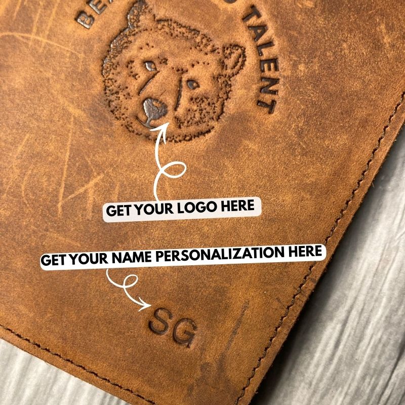 Brown leather wallet with embossed logo and text on a wooden surface