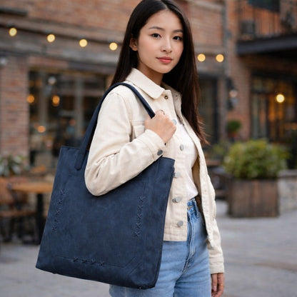 Woman holding a navy blue tote bag in an urban setting