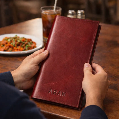 Person holding a red leather menu with &