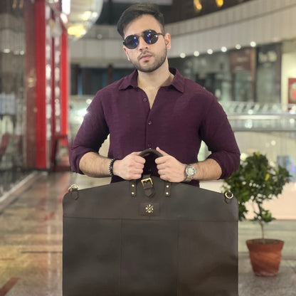 Man holding a black garment bag in an indoor setting