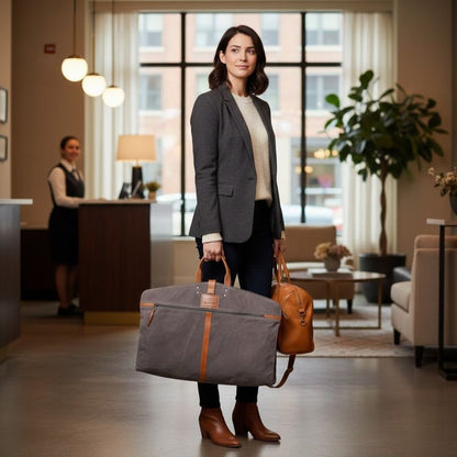 Woman holding a gray bag and brown leather suitcase in a hotel lobby.