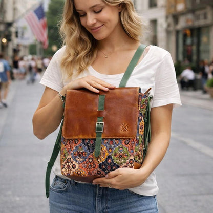 Woman holding a brown leather sling crossbody bag with colorful pattern on a city street.
