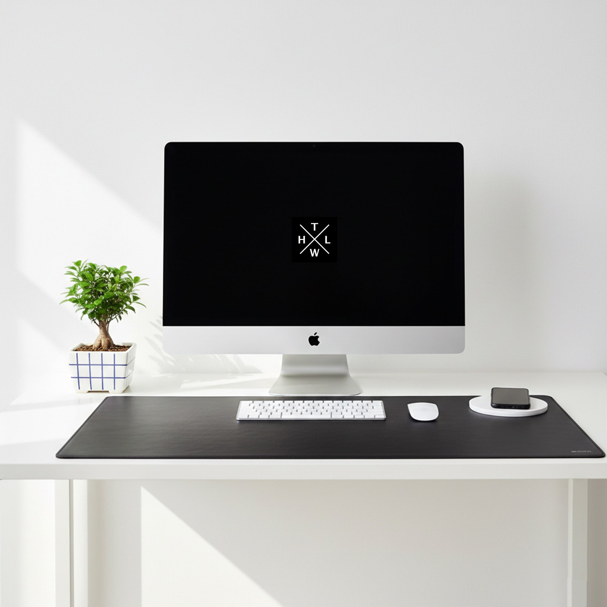 Modern desk setup with a computer monitor, keyboard, and mouse on a white surface.