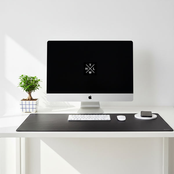 Modern desk setup with a computer monitor, keyboard, and mouse on a white surface.